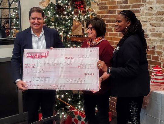 Carlos Liriano (left), Lost Pines Toyota owner, hands a check of $10,000 to representatives of Bastrop County Cares during a December 2022 presentation.   Courtesy photo