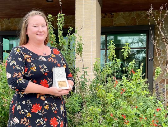 Elizabeth Marzec with her new trophy, in front of the center’s pollinator garden that she helped develop. Photo by Niko Demetriou