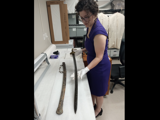 Museum Collections Manager Heather Bloom examines a Civil War-era sword in archives before displaying it in the Bastrop History Museum. Photo courtesy Bastrop County Historical Society