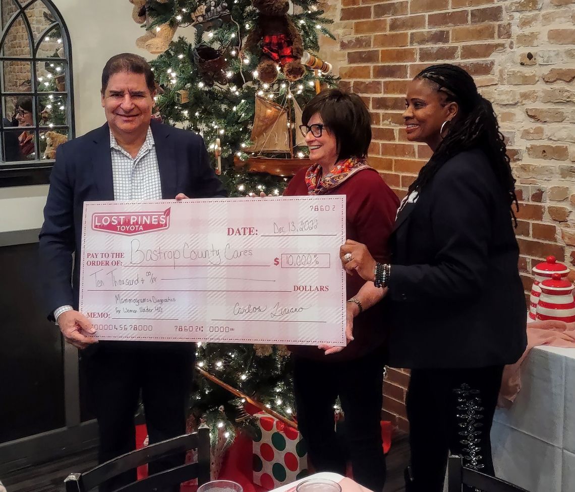 Carlos Liriano (left), Lost Pines Toyota owner, hands a check of $10,000 to representatives of Bastrop County Cares during a December 2022 presentation.   Courtesy photo