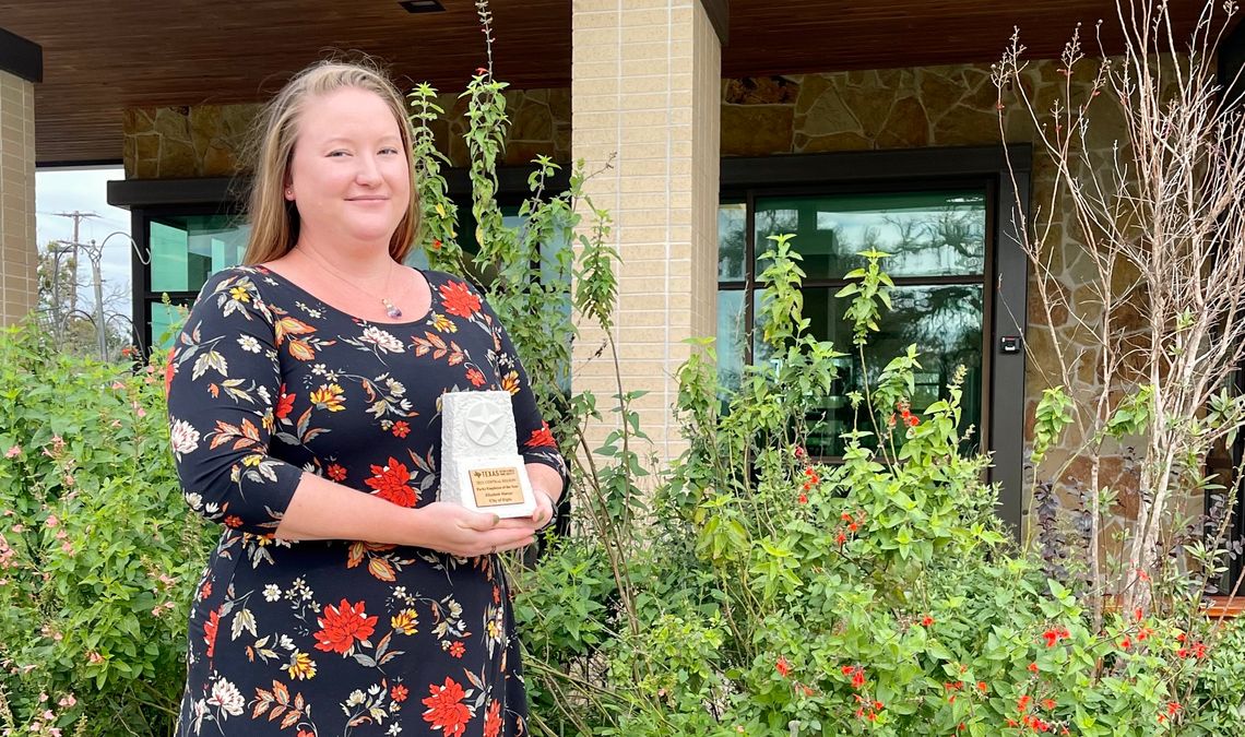 Elizabeth Marzec with her new trophy, in front of the center’s pollinator garden that she helped develop. Photo by Niko Demetriou