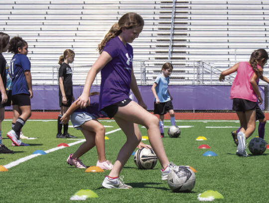 Girls campers do a cone drill to improve their dribbling skills on June 8 during the Wildcats Youth Soccer Camp hosted at Wildcat Stadium. Photo by Erin Anderson