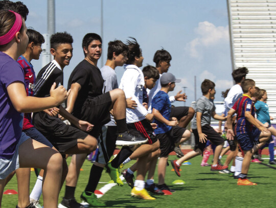 Elgin campers do a high-knee exercise in warmups on June 8 during the Wildcats Youth Soccer Camp hosted at Wildcat Stadium. Photo by Erin Anderson