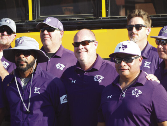 Elgin High School varsity football head coach Heath Clawson happily poses for a photo with fellow members of his coaching staff on Thursday, Aug. 10 during the annual Meet The Wildcats event held at Veterans’ Memorial Park in Downtown Elgin. Photo by Andrew Salmi