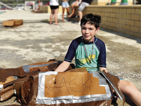 Children’s race winner Teddy Menke poses with the remains of his boat, “Jack.” Photo by Niko Demetriou