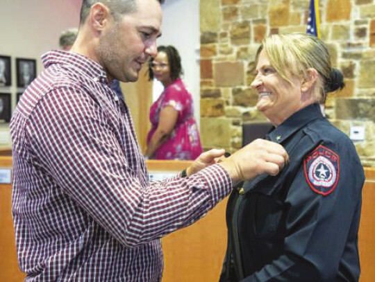 Vicky Steffanic has her police chief badge pinned on her uniform by husband Matthew Steffanic during the Bastrop City Council meeting April 11. Courtesy photo