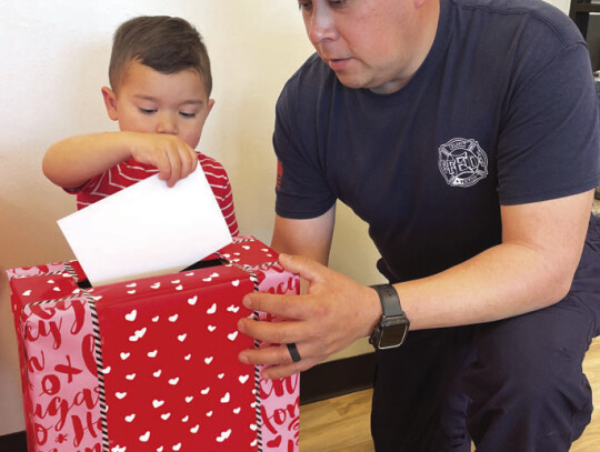 Elgin Fire Department’s Randy Reyna sending out a letter for hospitalized children alongside one of the city’s youths. Photo courtesy Elgin Parks and Recreation Department