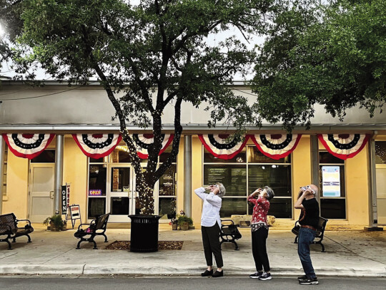 Main Street streetlamps cut on and off for the few minutes the moon passed in front of the sun. Bastrop Museum volunteers make use of the eclipse glasses they were handing out to the public. Courtesy photo